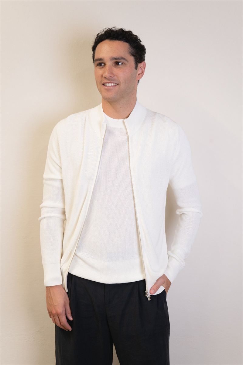 Uomo con cardigan in maglia bianco e pantaloni neri