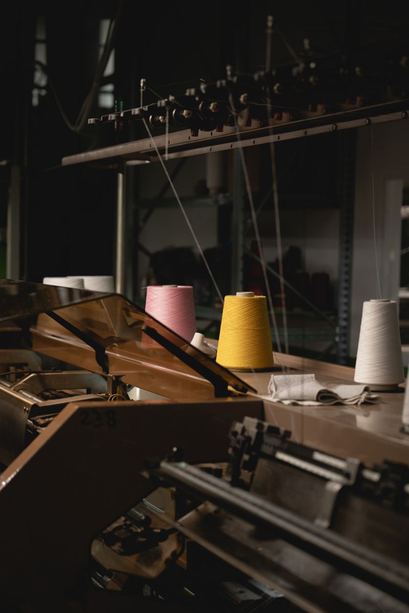Pink, yellow and white yarn cones on a knitting machine