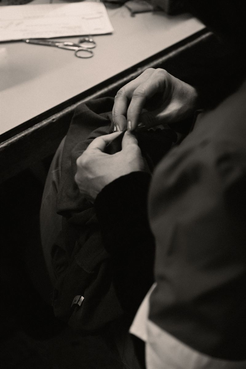 Hands sewing a knitted garment by hand