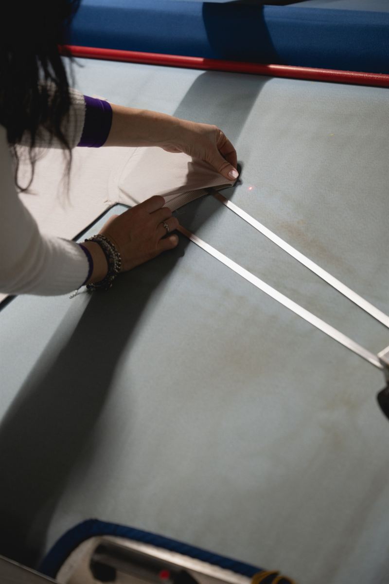 Hands aligning a garment to laser guides to check its measurements