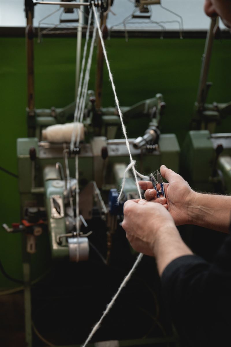 Hands knotting yarn with small clippers