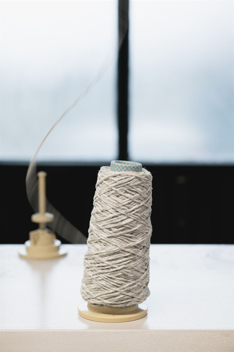 Cone of grey melange yarn on a cone holder