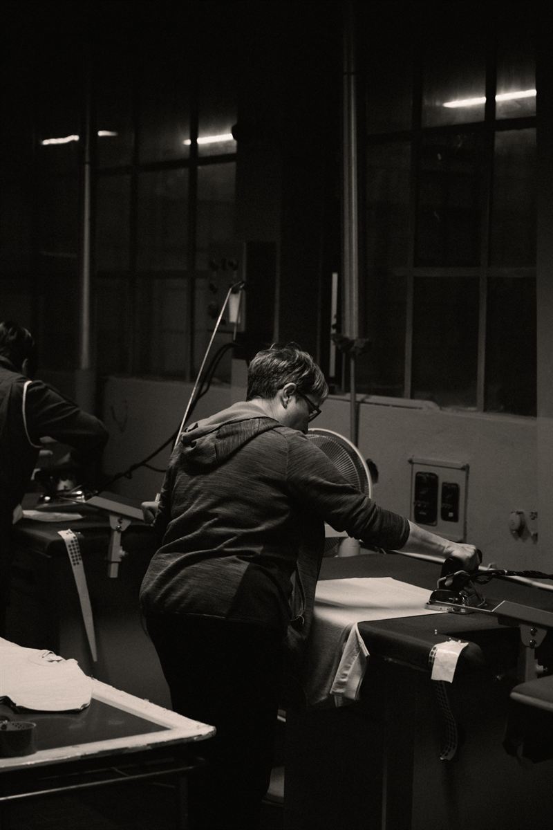 A worker pressing a garment at the ironing station