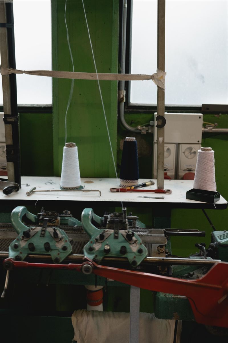 Hand-operated knitting machine with yarn cones and tools